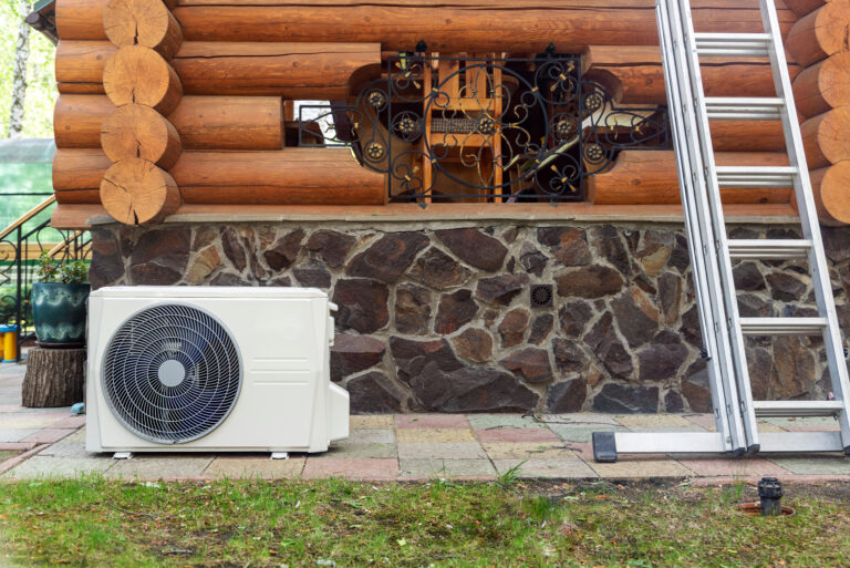 New modern HVAC air conditioning external compressor unit preapred for installation or replacement near wall of wooden log residential country cottage. Ladder and equipment for service and maintenance